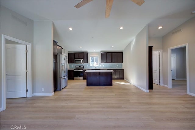 kitchen featuring appliances with stainless steel finishes, a center island, light hardwood / wood-style flooring, and dark brown cabinetry