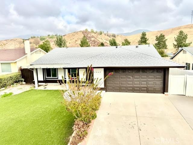 ranch-style house with a mountain view, a front yard, and a garage