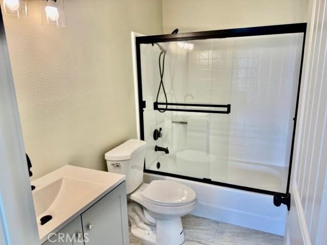 full bathroom featuring vanity, toilet, and combined bath / shower with glass door