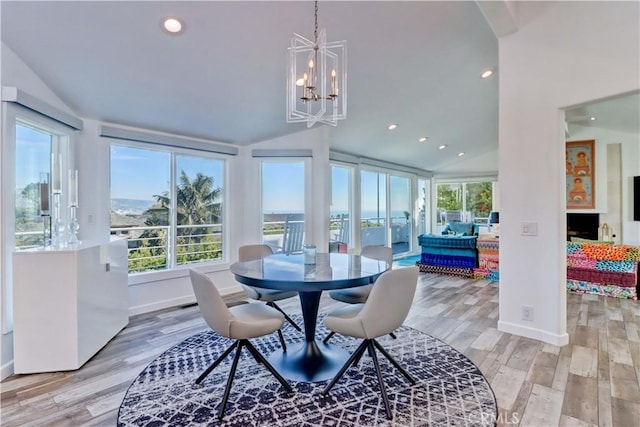 dining room with light wood-type flooring, an inviting chandelier, and vaulted ceiling