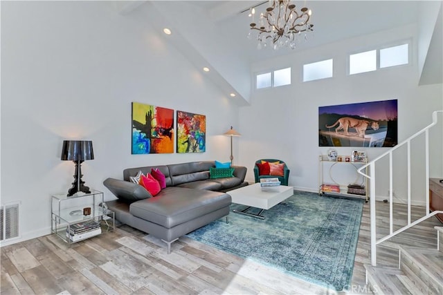 living room with hardwood / wood-style floors, a notable chandelier, and a towering ceiling