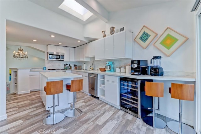 kitchen featuring light wood-type flooring, beverage cooler, white cabinets, and backsplash