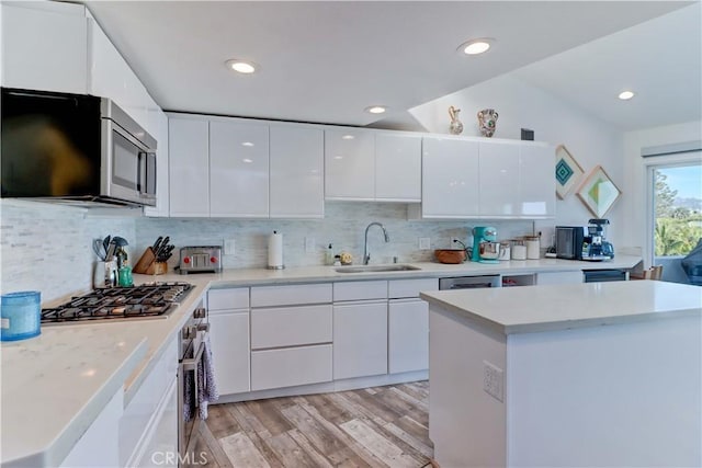 kitchen with decorative backsplash, sink, light hardwood / wood-style flooring, stainless steel appliances, and white cabinets