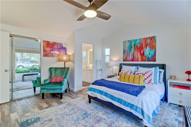 bedroom with vaulted ceiling, ceiling fan, connected bathroom, and hardwood / wood-style floors