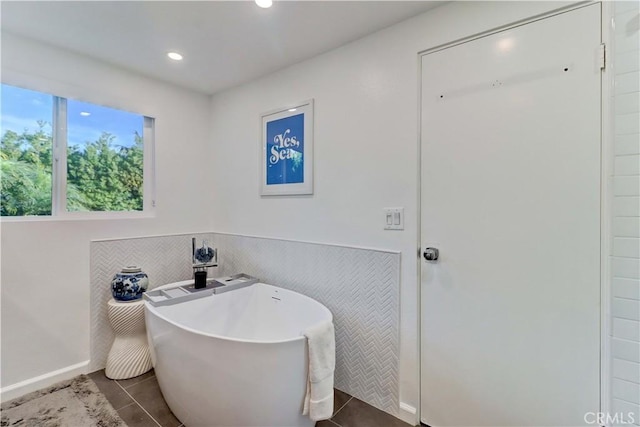 bathroom with tile patterned flooring and a bath