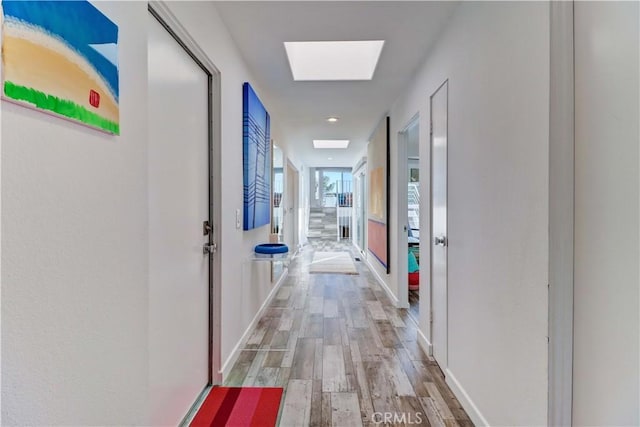 hallway featuring a skylight and light hardwood / wood-style floors