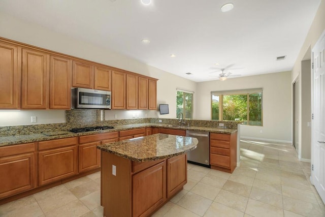 kitchen featuring tasteful backsplash, a kitchen island, kitchen peninsula, appliances with stainless steel finishes, and stone countertops