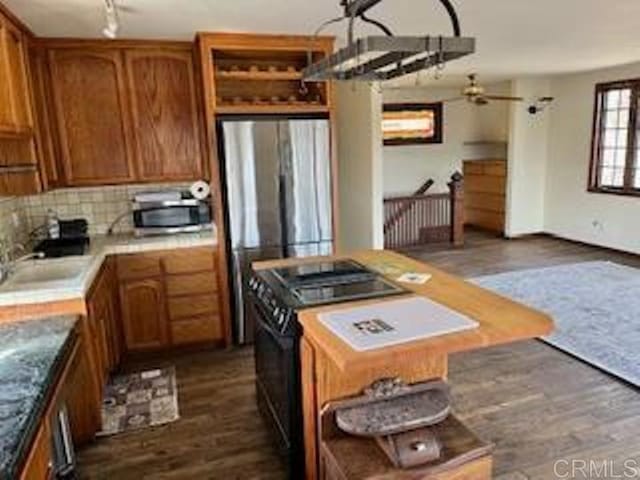 kitchen featuring stainless steel fridge, sink, black range, and dark hardwood / wood-style floors