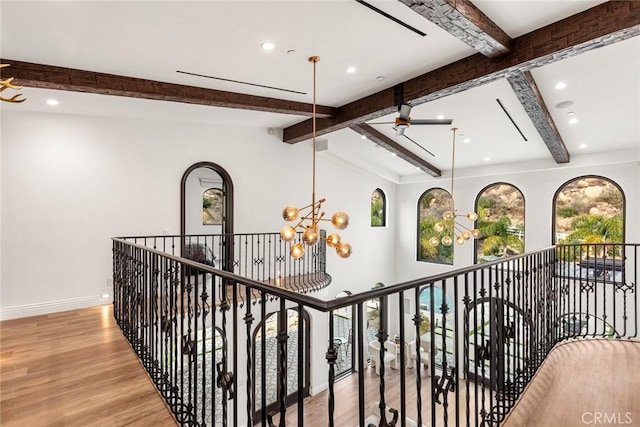 hallway with light wood-type flooring, lofted ceiling with beams, and a notable chandelier