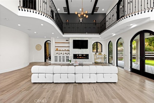 living room featuring light hardwood / wood-style floors, a towering ceiling, and french doors