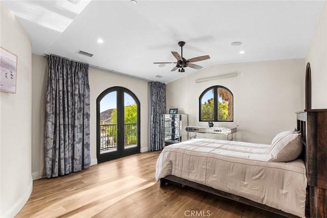 bedroom with french doors, light wood-type flooring, multiple windows, and lofted ceiling