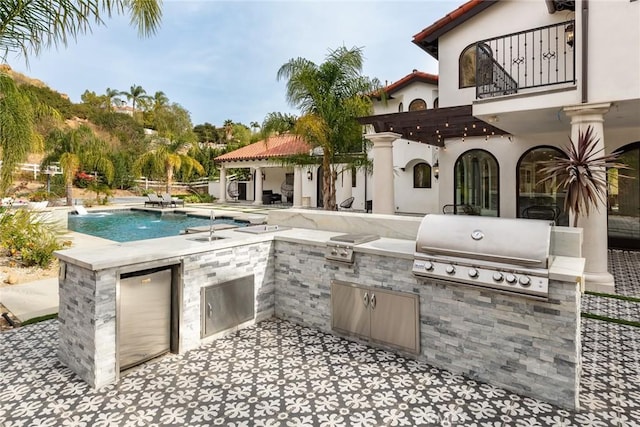 view of patio / terrace with pool water feature, a balcony, exterior kitchen, and grilling area