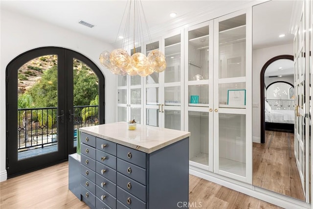 walk in closet with french doors and light hardwood / wood-style flooring