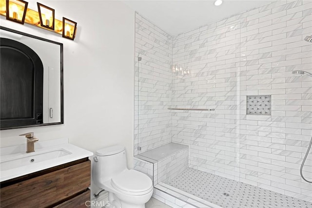 bathroom with a tile shower, vanity, and toilet