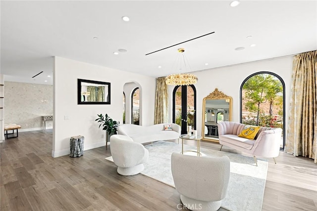 living room with a healthy amount of sunlight, a notable chandelier, and light wood-type flooring