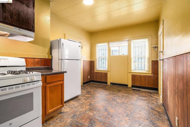 kitchen with wooden walls, range hood, and white appliances