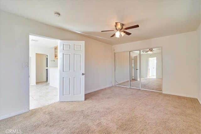 unfurnished bedroom featuring ceiling fan, light colored carpet, a closet, and lofted ceiling