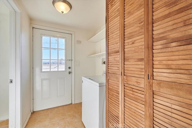 clothes washing area with washer / dryer and light tile patterned floors