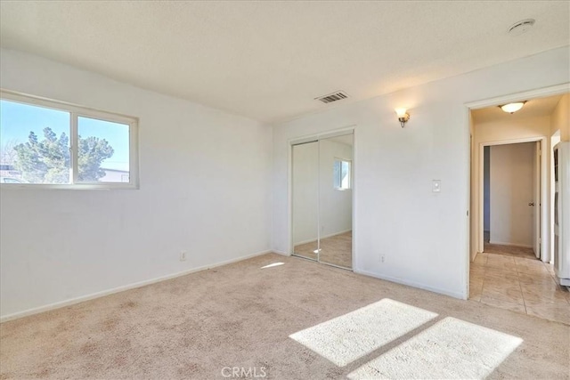 unfurnished bedroom featuring light colored carpet and a closet