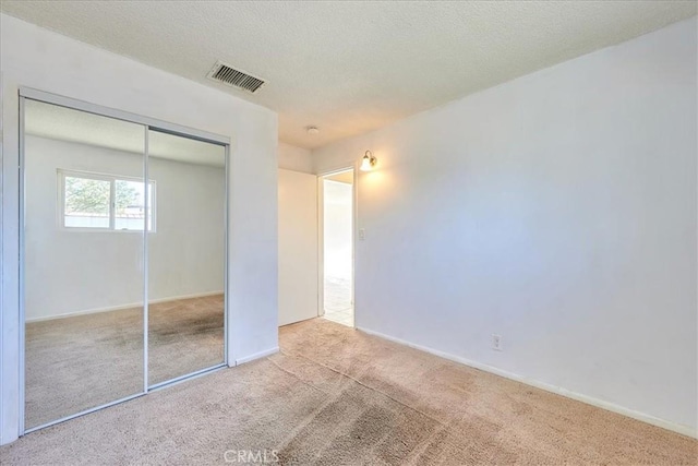 unfurnished bedroom with light carpet and a closet