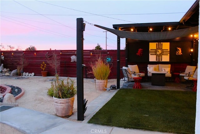 patio terrace at dusk featuring a yard