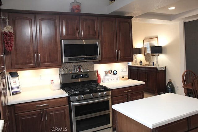 kitchen with stainless steel appliances, a raised ceiling, tasteful backsplash, dark brown cabinets, and a center island