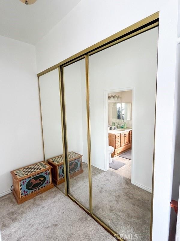 interior space featuring light carpet, connected bathroom, and a closet