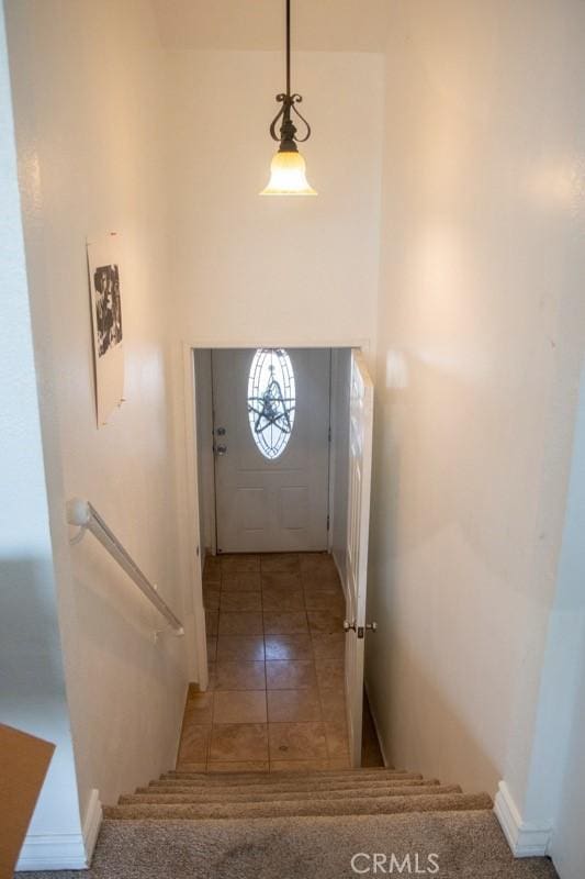 stairs featuring a towering ceiling and tile patterned flooring