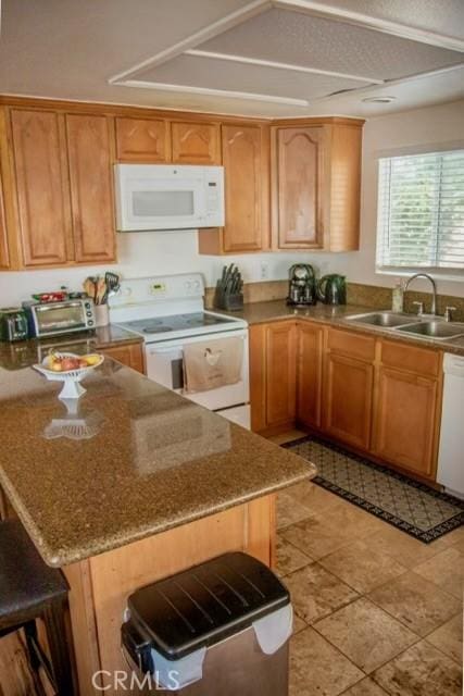 kitchen featuring sink, white appliances, light tile patterned floors, and a breakfast bar area