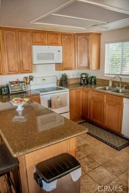 kitchen featuring white appliances, stone counters, a kitchen bar, and a sink