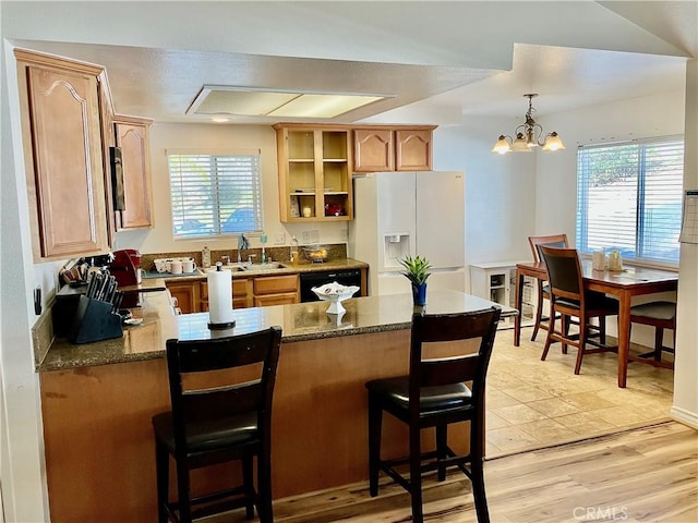 kitchen with black dishwasher, white refrigerator with ice dispenser, plenty of natural light, and a peninsula