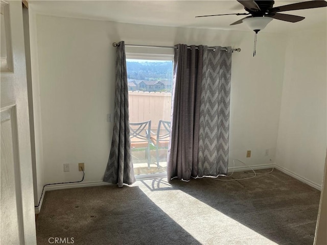 carpeted spare room with ceiling fan and baseboards