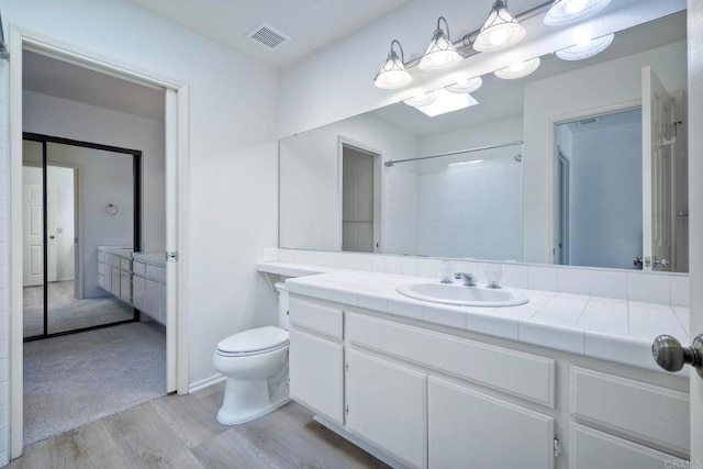 bathroom with vanity, hardwood / wood-style flooring, a shower, and toilet