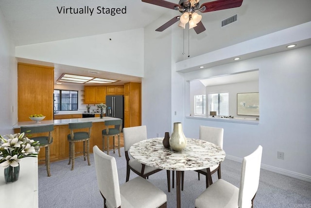 carpeted dining space featuring ceiling fan and high vaulted ceiling