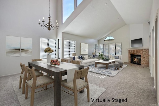 dining area featuring an inviting chandelier, a brick fireplace, high vaulted ceiling, and carpet flooring