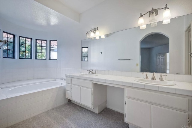 bathroom with vanity and tiled bath