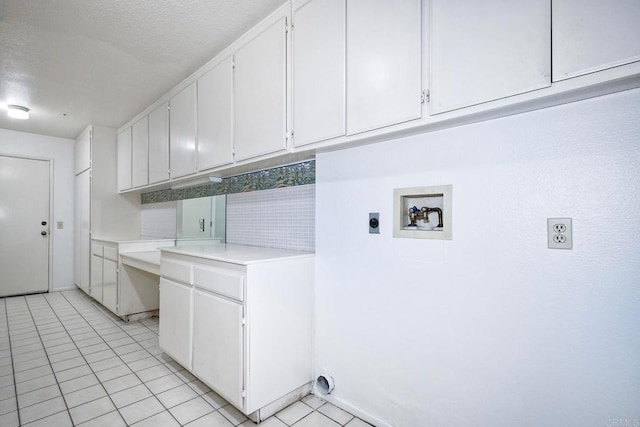 clothes washing area featuring cabinets, light tile patterned floors, hookup for a washing machine, hookup for an electric dryer, and a textured ceiling