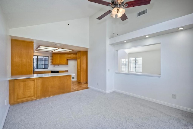 kitchen featuring high vaulted ceiling, light colored carpet, kitchen peninsula, and ceiling fan