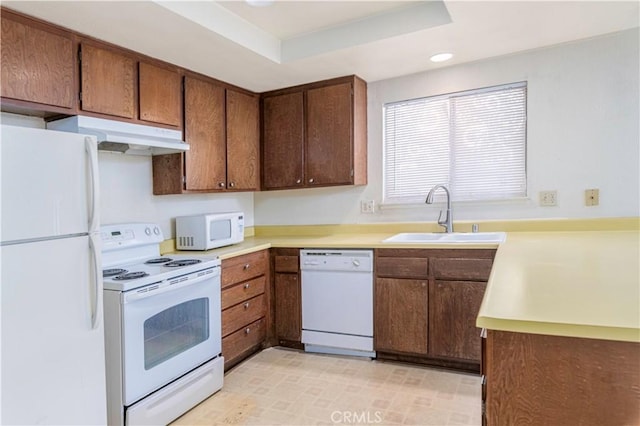 kitchen featuring a raised ceiling, sink, and white appliances