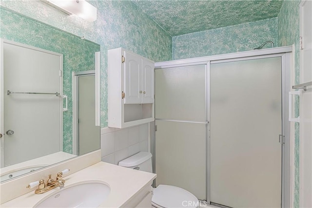 bathroom with a shower with door, vanity, and toilet