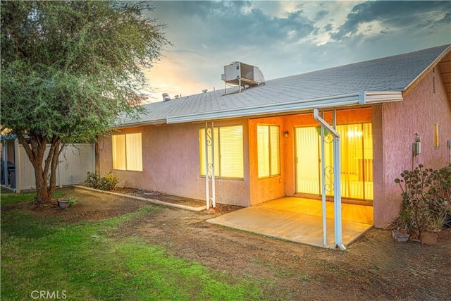 back house at dusk featuring a patio area and central air condition unit