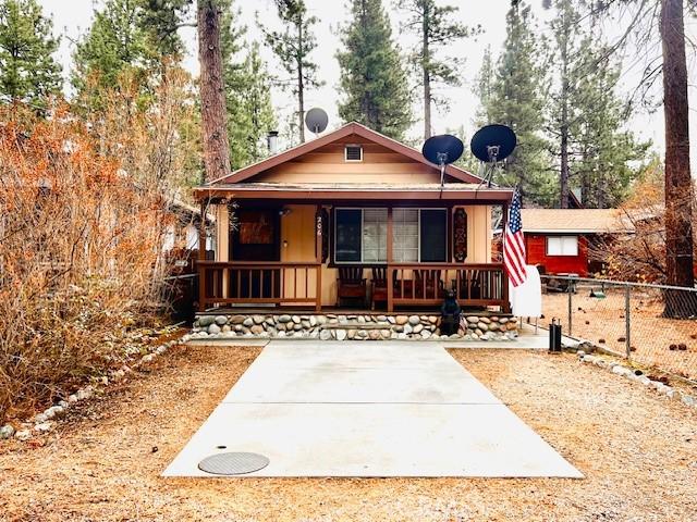 view of front of home with covered porch, driveway, and fence