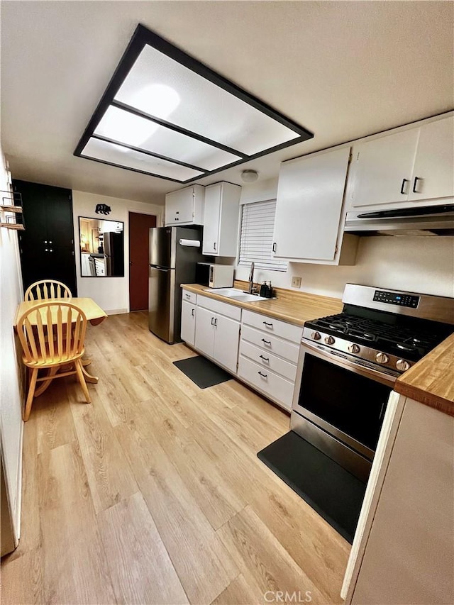 kitchen featuring butcher block countertops, white cabinetry, stainless steel appliances, and light wood-type flooring