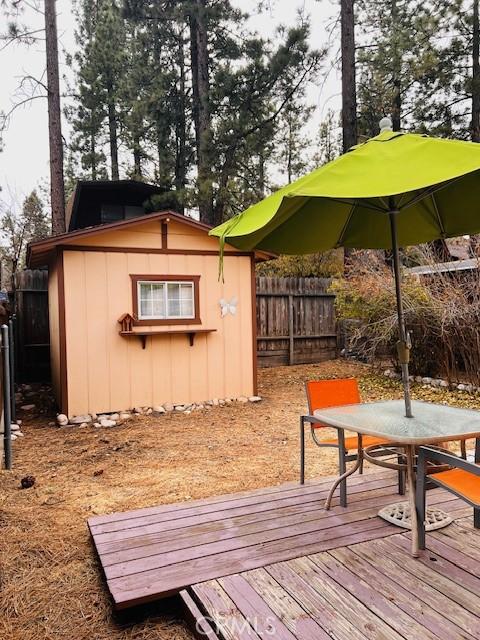 206 E Barker Blvd, Big Bear City, CA 92314 - wooden deck with a fenced backyard, an outbuilding, a storage shed, and outdoor dining space