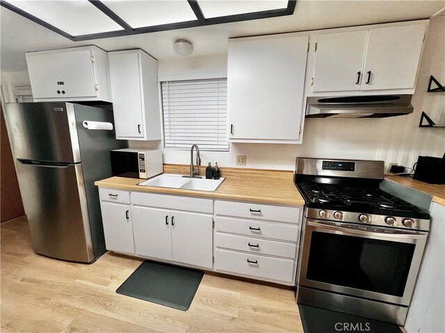 206 E Barker Blvd, Big Bear City, CA 92314 - kitchen featuring appliances with stainless steel finishes, white cabinetry, a sink, under cabinet range hood, and light wood-style flooring