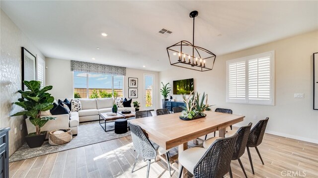 dining space featuring a notable chandelier and light wood-type flooring