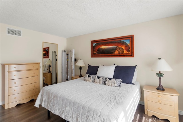 bedroom featuring a textured ceiling and dark hardwood / wood-style flooring