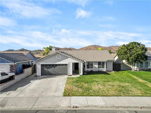 ranch-style home with a mountain view, a front lawn, and a garage