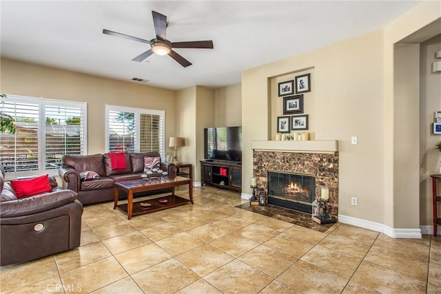 living room with light tile patterned floors, visible vents, a ceiling fan, a high end fireplace, and baseboards