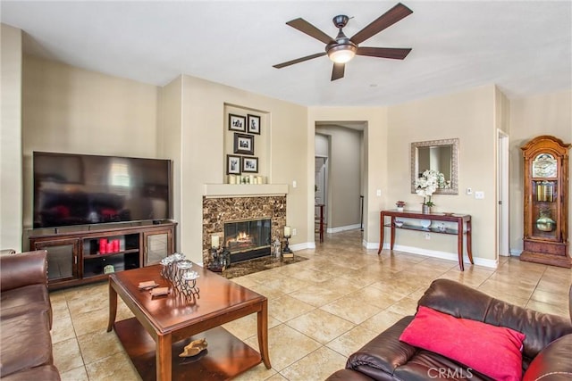 tiled living area with baseboards, a ceiling fan, and a high end fireplace